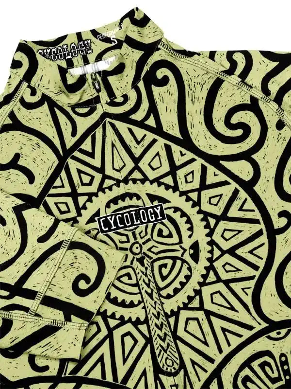 Men's cycling jersey with bold black tribal and gear pattern on light green fabric, featuring zippered collar and brand logo.