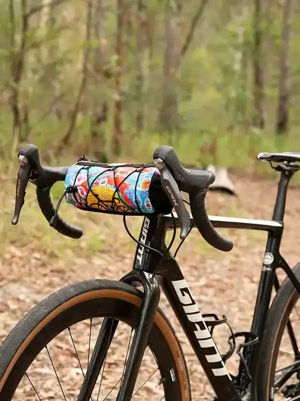Colorful cycling frame bag on bike handlebars in forest trail