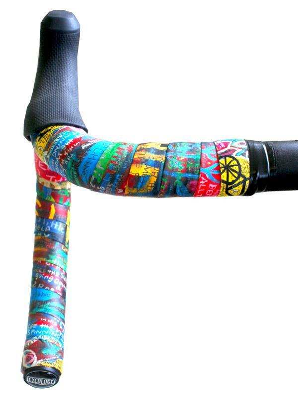 Colorful graffiti-style cycling handlebar tape with black end plugs, designed for road bike comfort and grip.