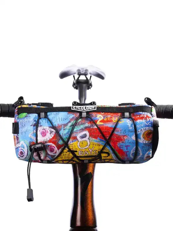Colorful graffiti-style cycling frame bag with '8 DAYS' print, mounted on bike handlebars for road rides