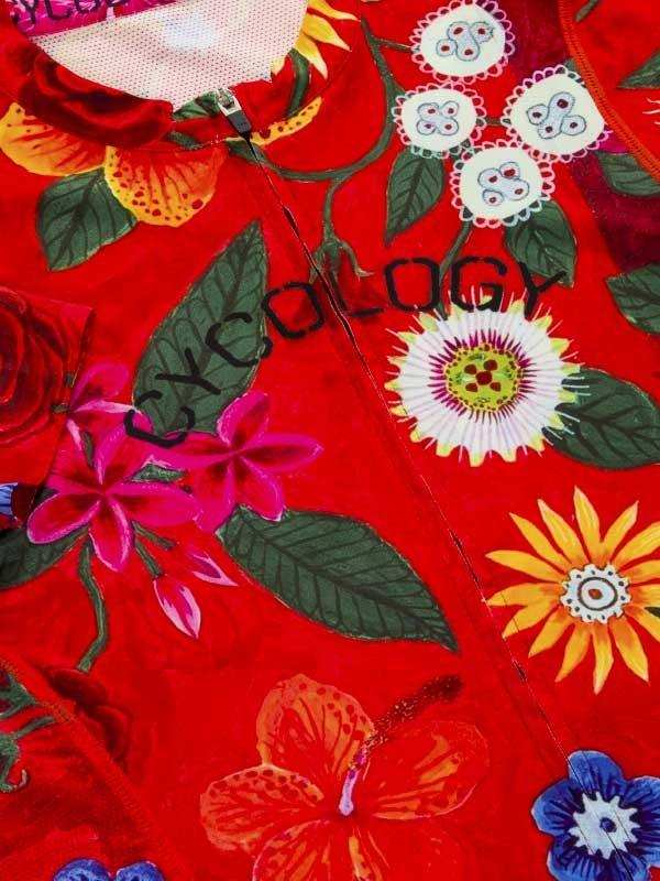 Vibrant red cycling jersey with tropical floral print and 'CYCOLOGY' branding, featuring hibiscus and passionflower designs.