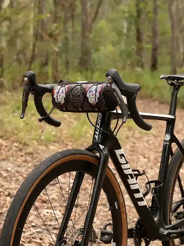 Cycling handlebar bag with sugar skull design on road bike in forest setting