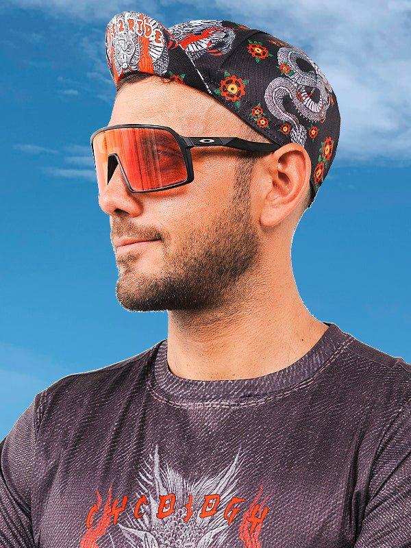 Man wearing cycling bandana and sunglasses, stylish men's cycling apparel under blue sky