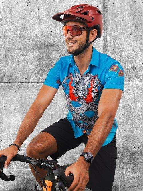 Man cycling in blue graphic jersey, red helmet, and sunglasses against concrete wall