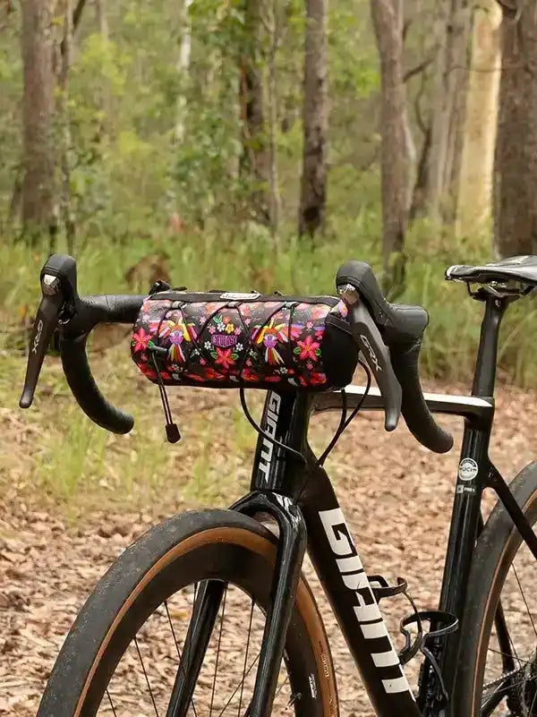 Floral patterned cycling handlebar bag on black road bike in forest trail