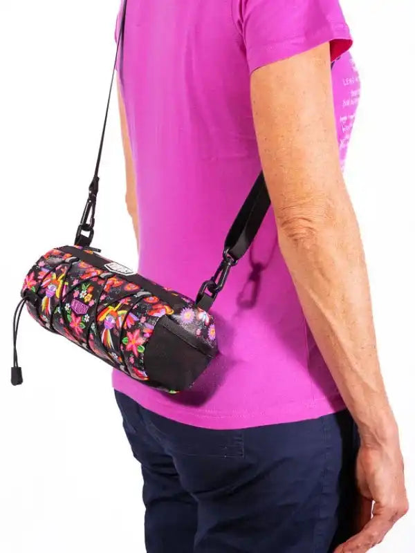 Colorful floral cycling bag with black straps worn crossbody by person in pink shirt