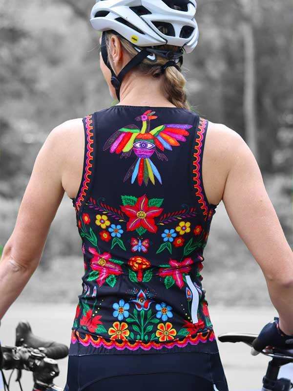 Woman wearing colorful floral cycling jersey with bird design, white helmet, on bike outdoors
