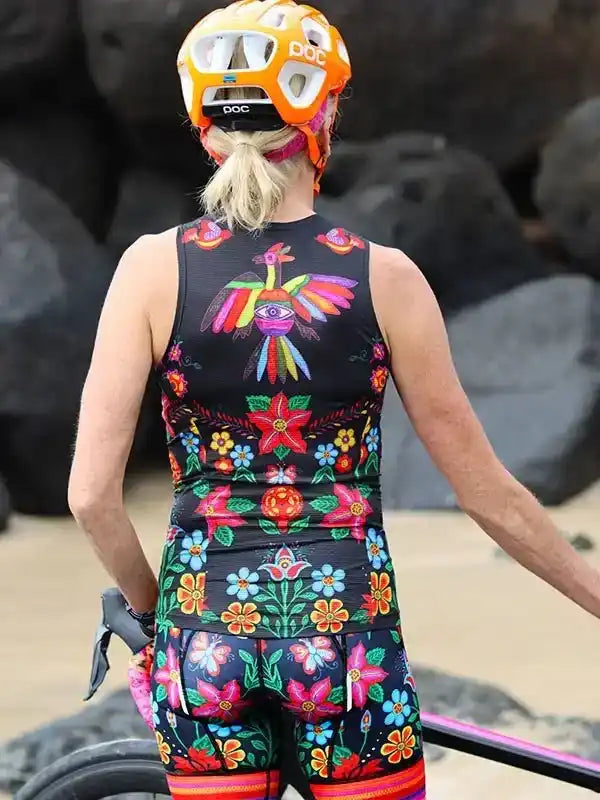 Woman in colorful floral cycling kit and POC helmet, back view on rocky trail