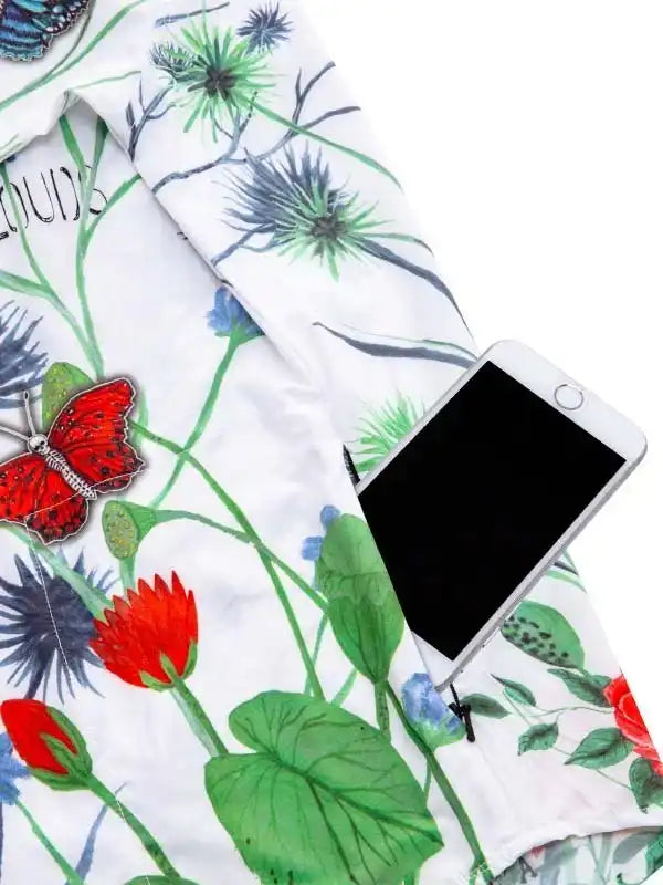 Women's floral cycling jersey with butterfly print, shown with smartphone for scale