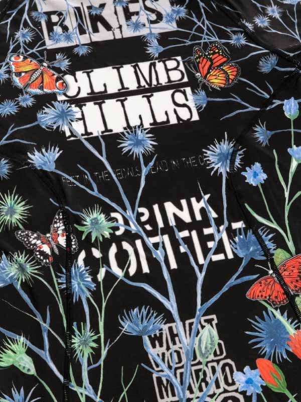 Black cycling jersey with floral and butterfly print, bold text 'CLIMB HILLS DRINK COFFEE' for cyclists