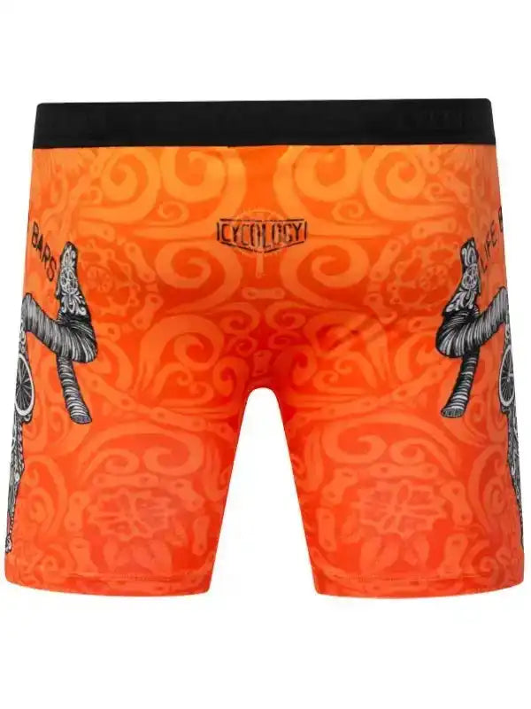 Orange cycling shorts with bold swirl pattern and bike graphic, featuring black waistband and brand logo.