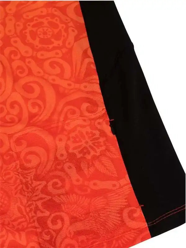 Vibrant orange cycling jersey with intricate chain and swirl pattern, black side panel detail