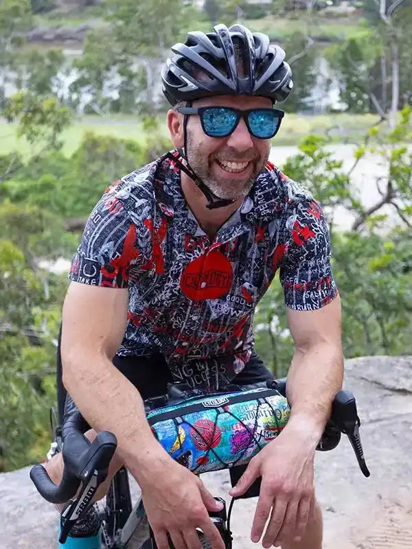 Man in colorful cycling jersey and helmet, smiling on bike outdoors