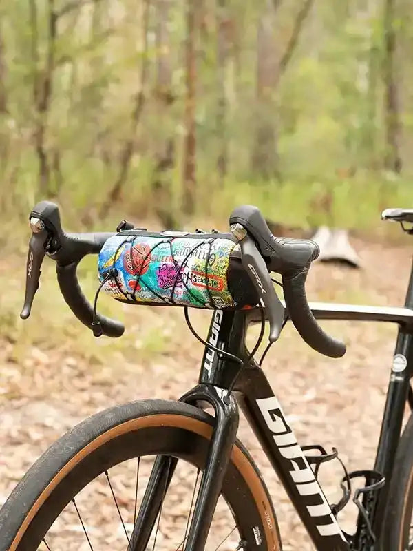 Colorful cycling handlebar bag on road bike in forest, ideal for bikepacking and outdoor rides
