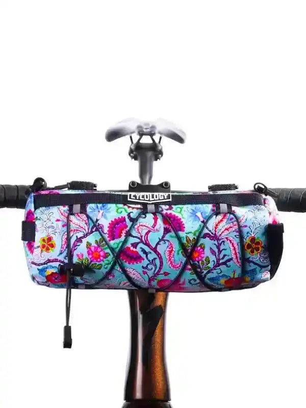 Colorful floral bike frame bag with black straps, mounted on handlebars for cycling storage