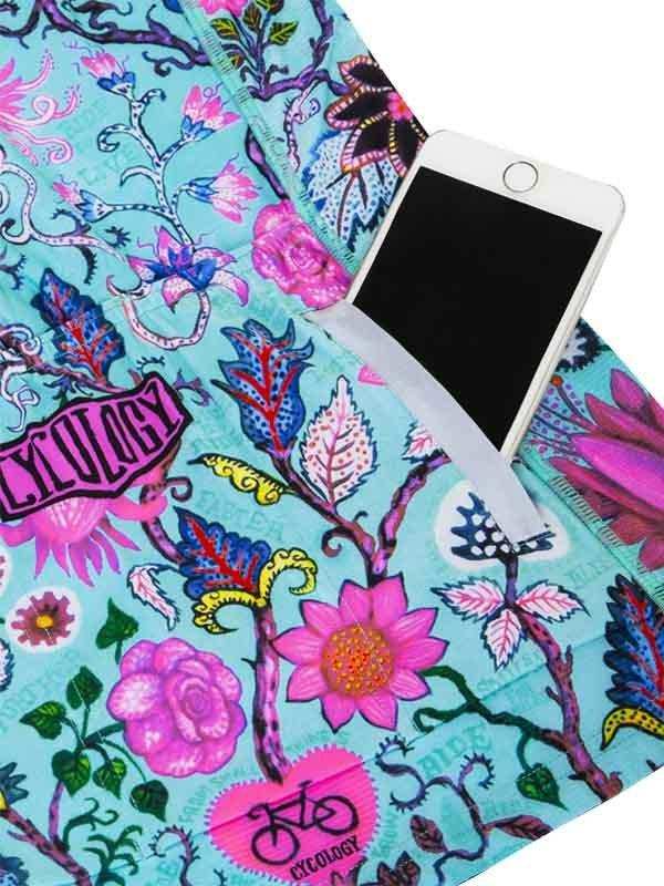 Vibrant floral cycling jersey with phone pocket, featuring bold pink and blue botanical print for women's bike wear.
