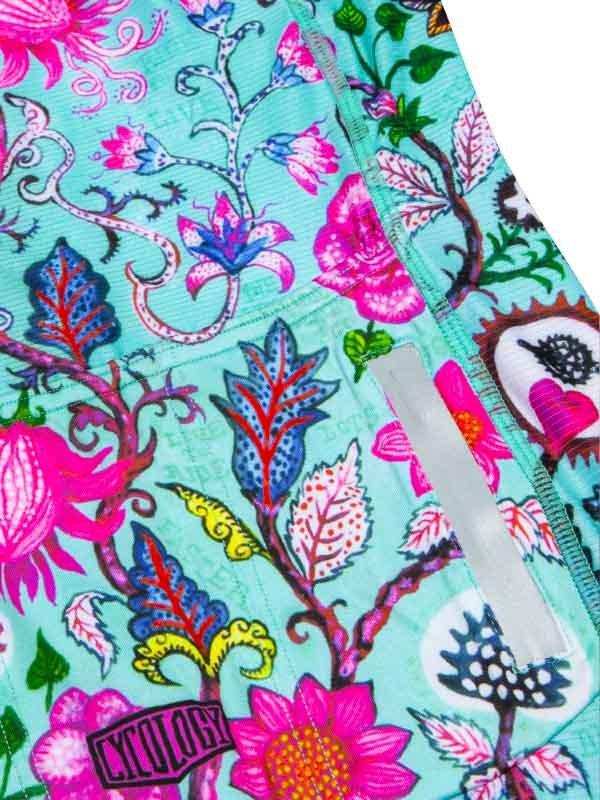 Vibrant floral cycling shorts with pink, blue, and green botanical print on teal fabric
