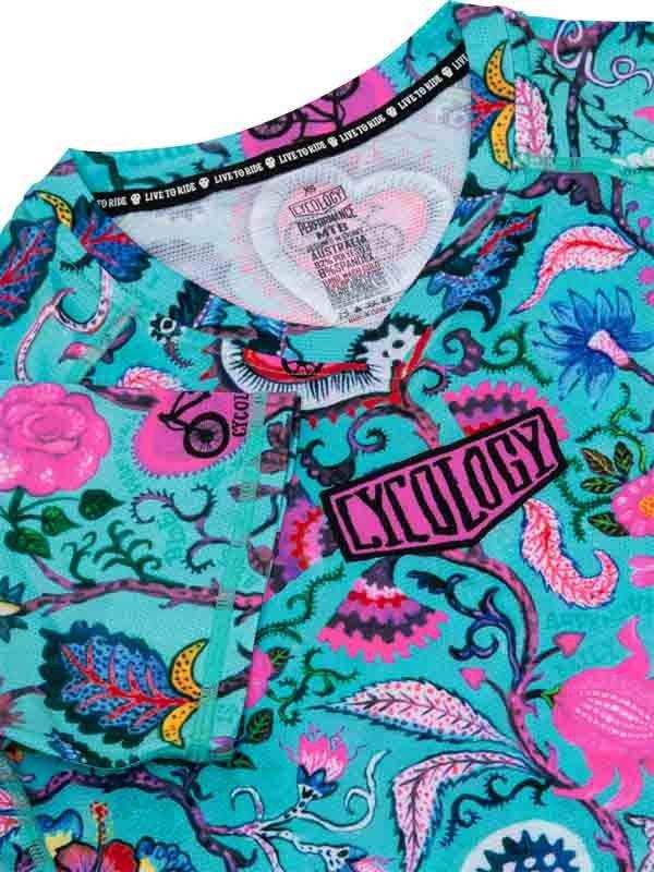 Vibrant turquoise cycling jersey with pink floral and bike graphics, featuring 'CYCOLOGY' logo and performance tag.