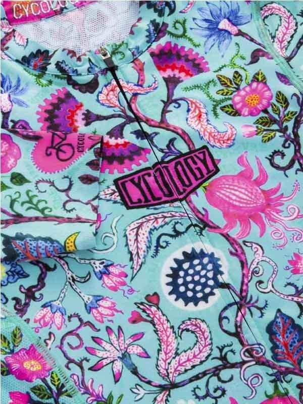 Vibrant floral cycling jersey with pink and blue botanical print, featuring zipper and brand patch detail.