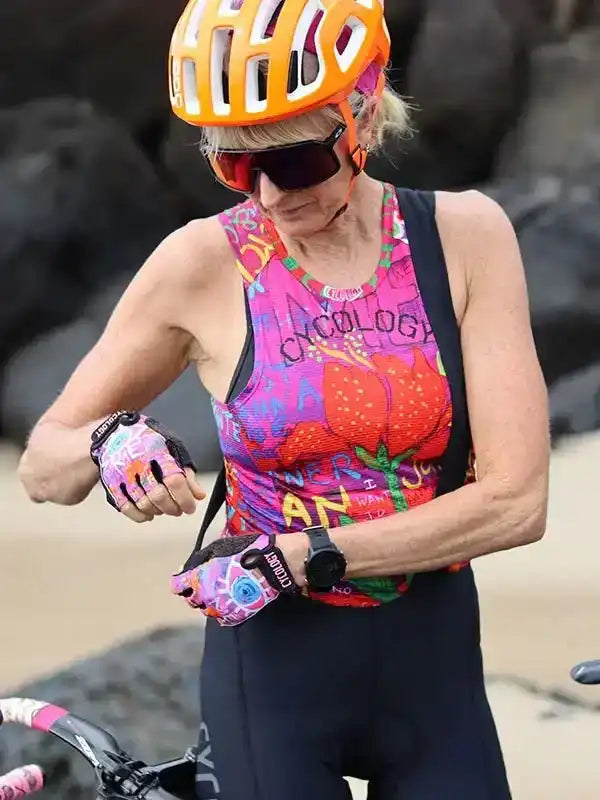 Woman in colorful cycling jersey and orange helmet checking smartwatch during ride