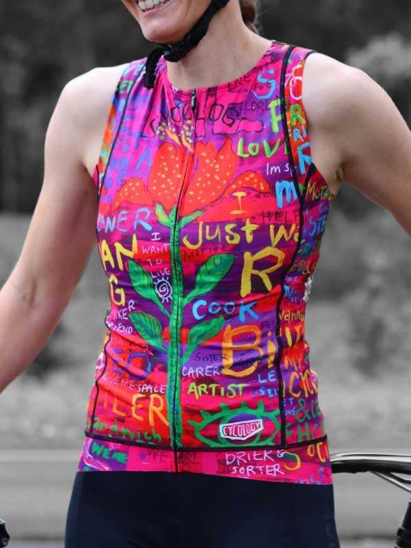 Woman wearing colorful graffiti-style cycling jersey with floral print and bold text, perfect for road biking.