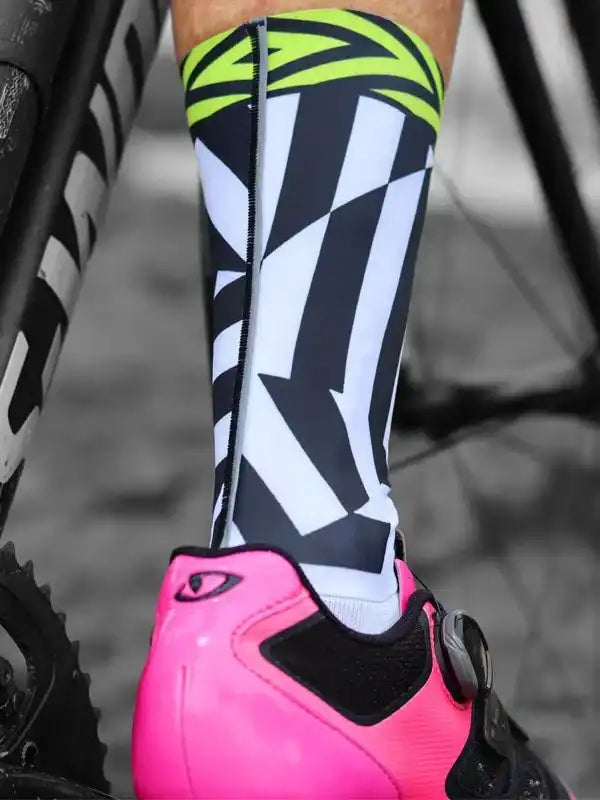 Cycling socks with bold black, white, and neon green geometric pattern, paired with pink cycling shoe