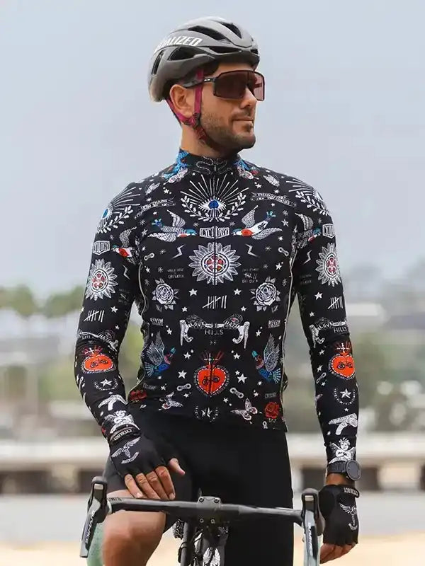 Man wearing black long-sleeve cycling jersey with tattoo-style graphics, helmet, and sunglasses on bike