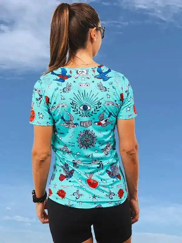Woman wearing turquoise cycling jersey with birds, stars, and eye design, ideal for road biking