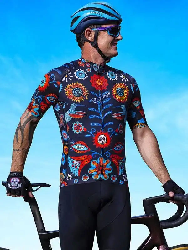 Man wearing colorful floral cycling jersey and helmet, holding bike outdoors