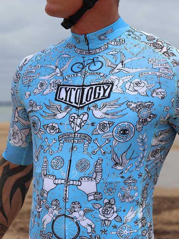 Men's blue cycling jersey with tattoo-style graphics, featuring birds, roses, and cycling motifs for road bike rides.